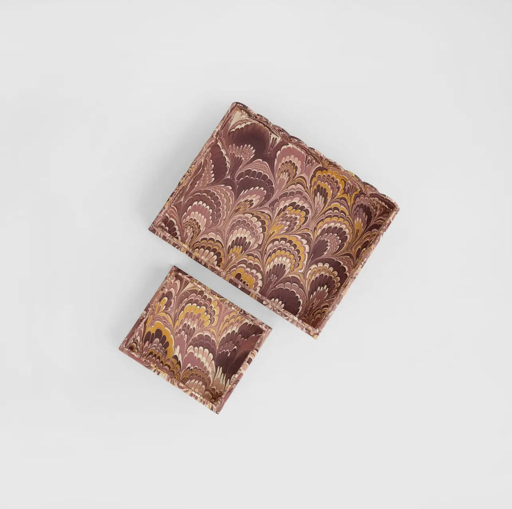 A pair of marbled burgundy and gold trays on a white background