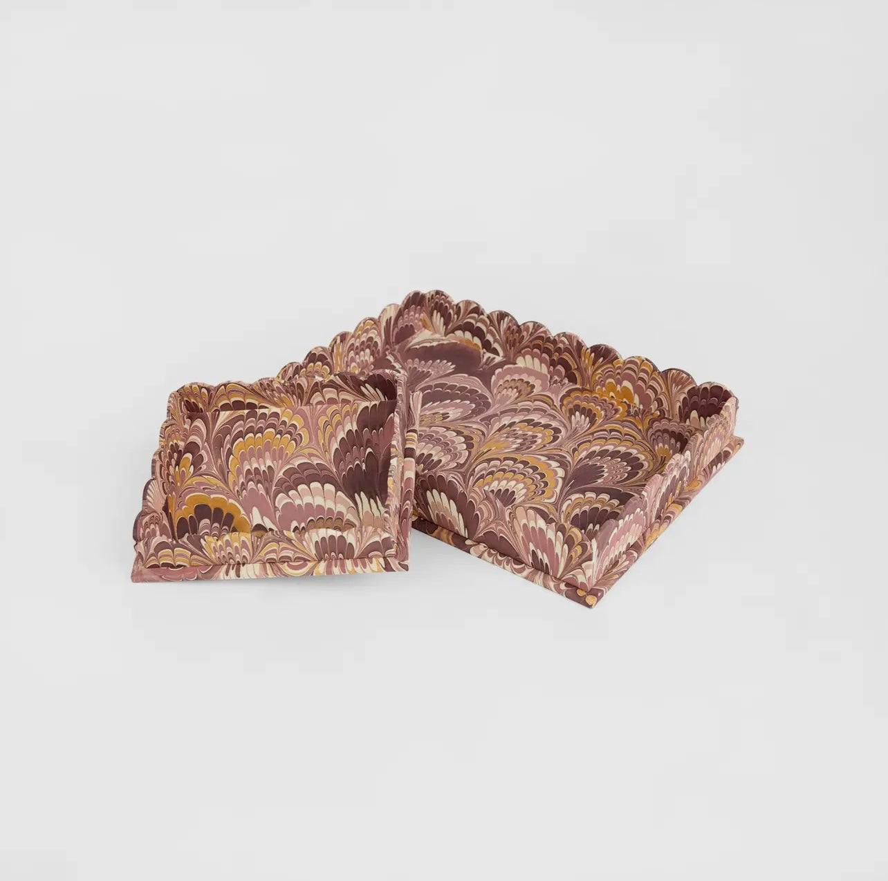 A pair of marbled burgundy and gold trays on a white background