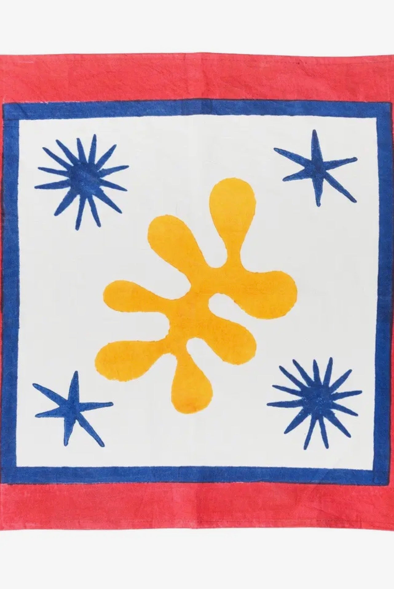 Napkin with a yellow motif and blue star patterns on a white background, bordered by red fabric.