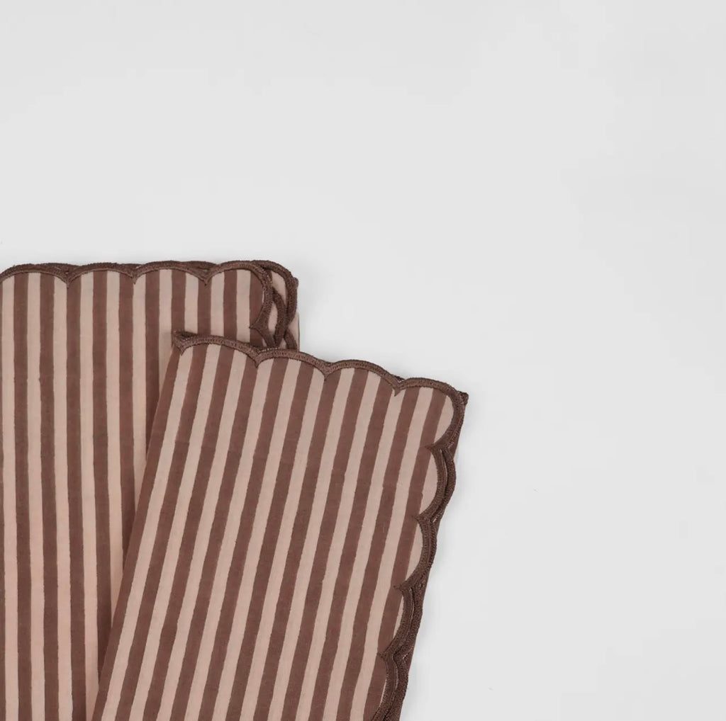 Pair of stripe rose and brown napkins with a scalloped edge on a white background