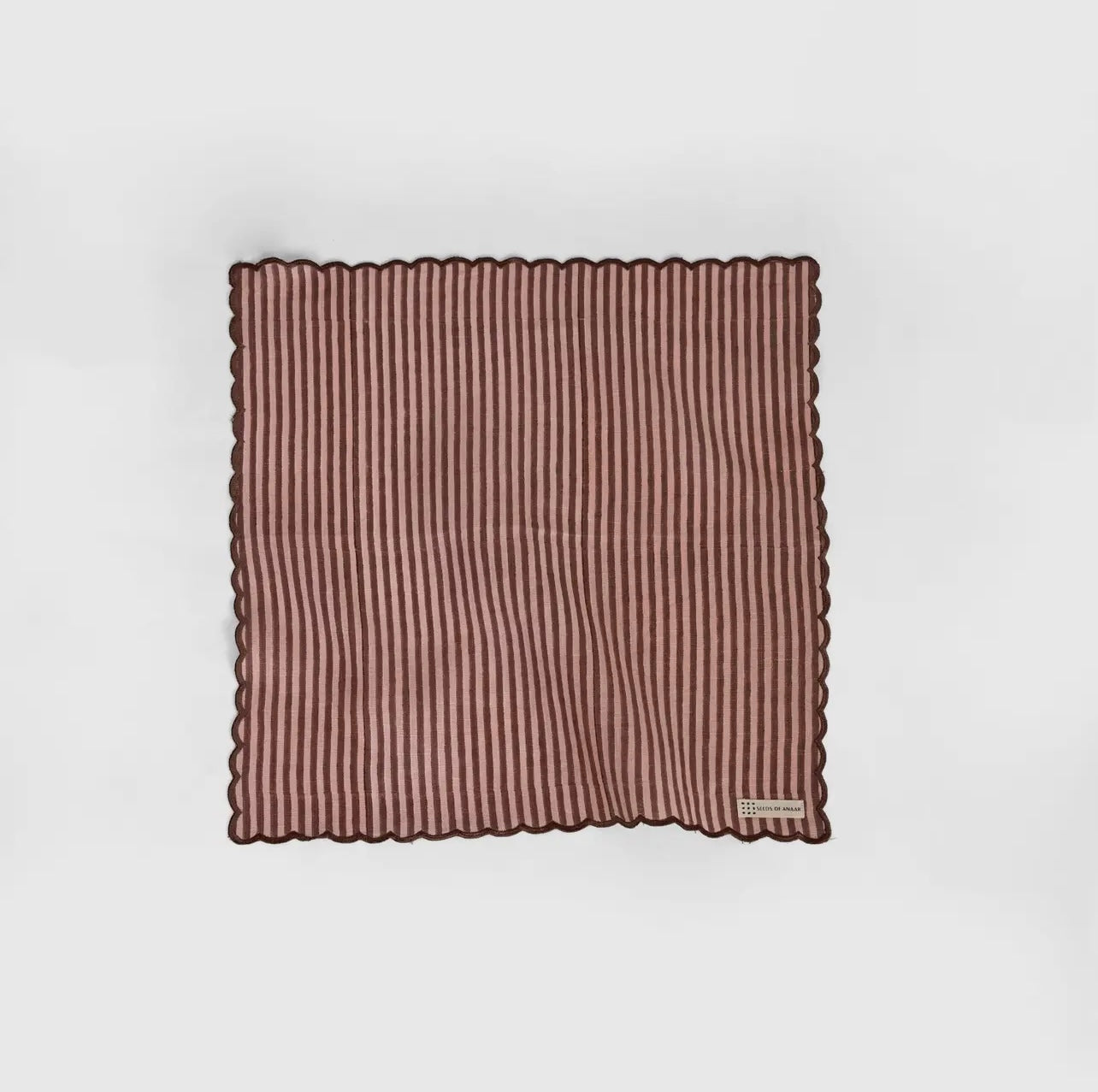 A stripe rose and brown napkin with a scalloped edge on a white background