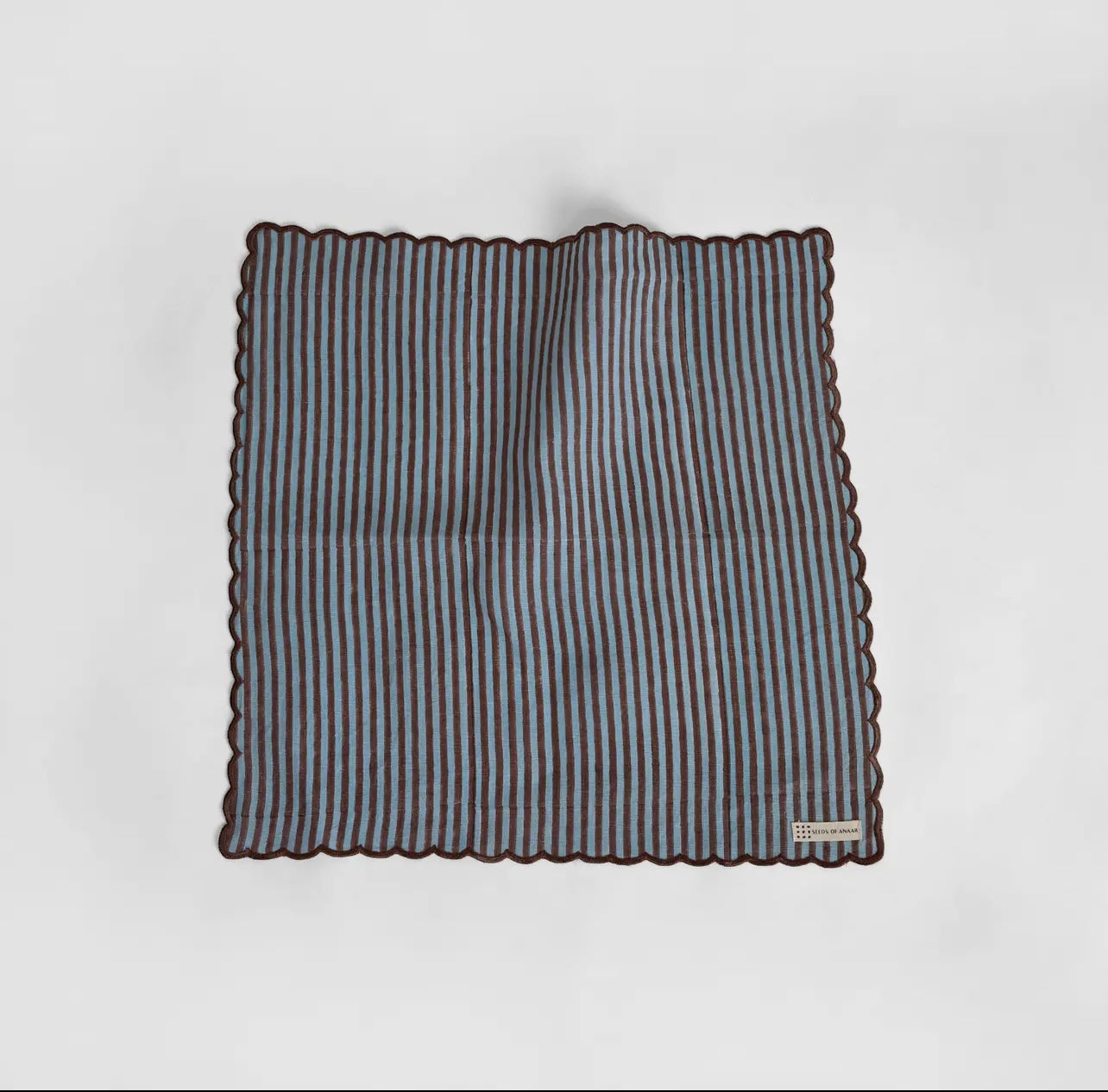 A blue and brown stripe napkin with scalloped edge on a white background. 