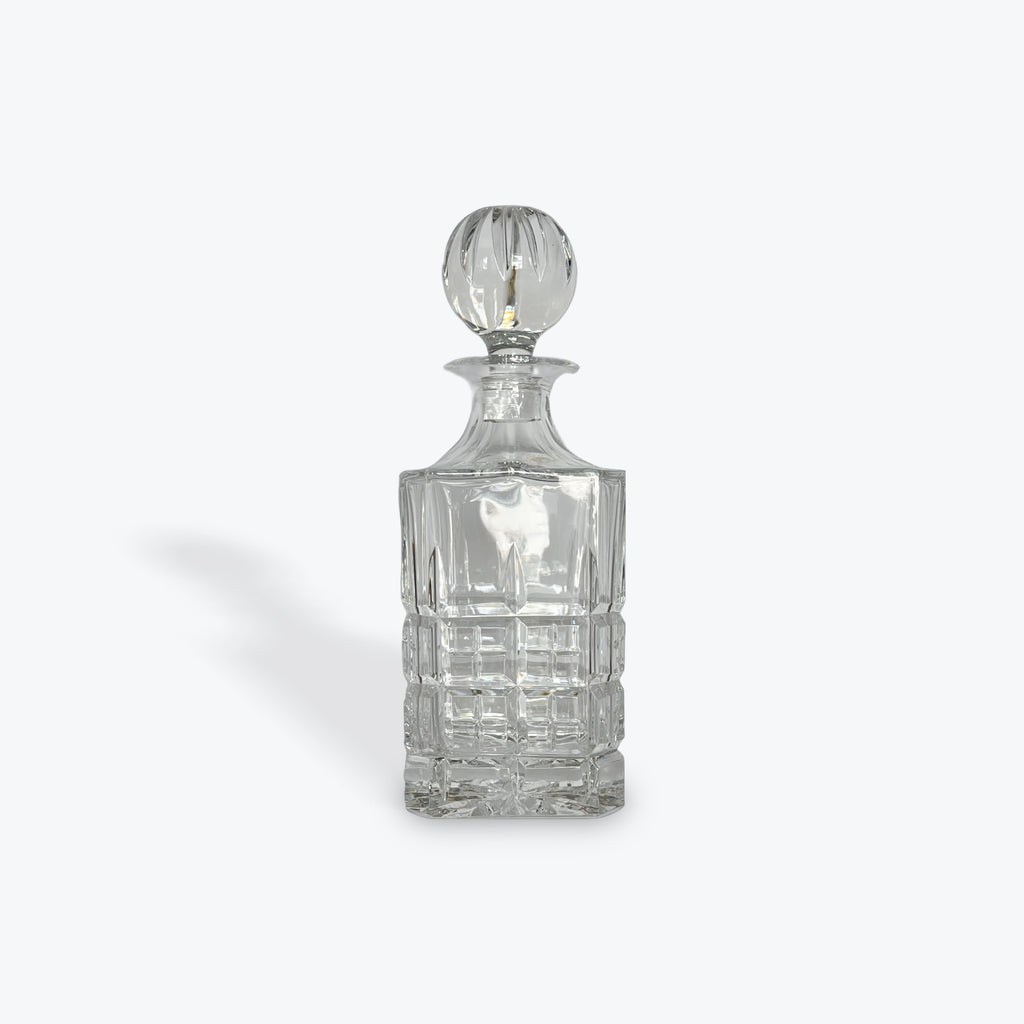 Clear glass decanter with a stopper on a white background