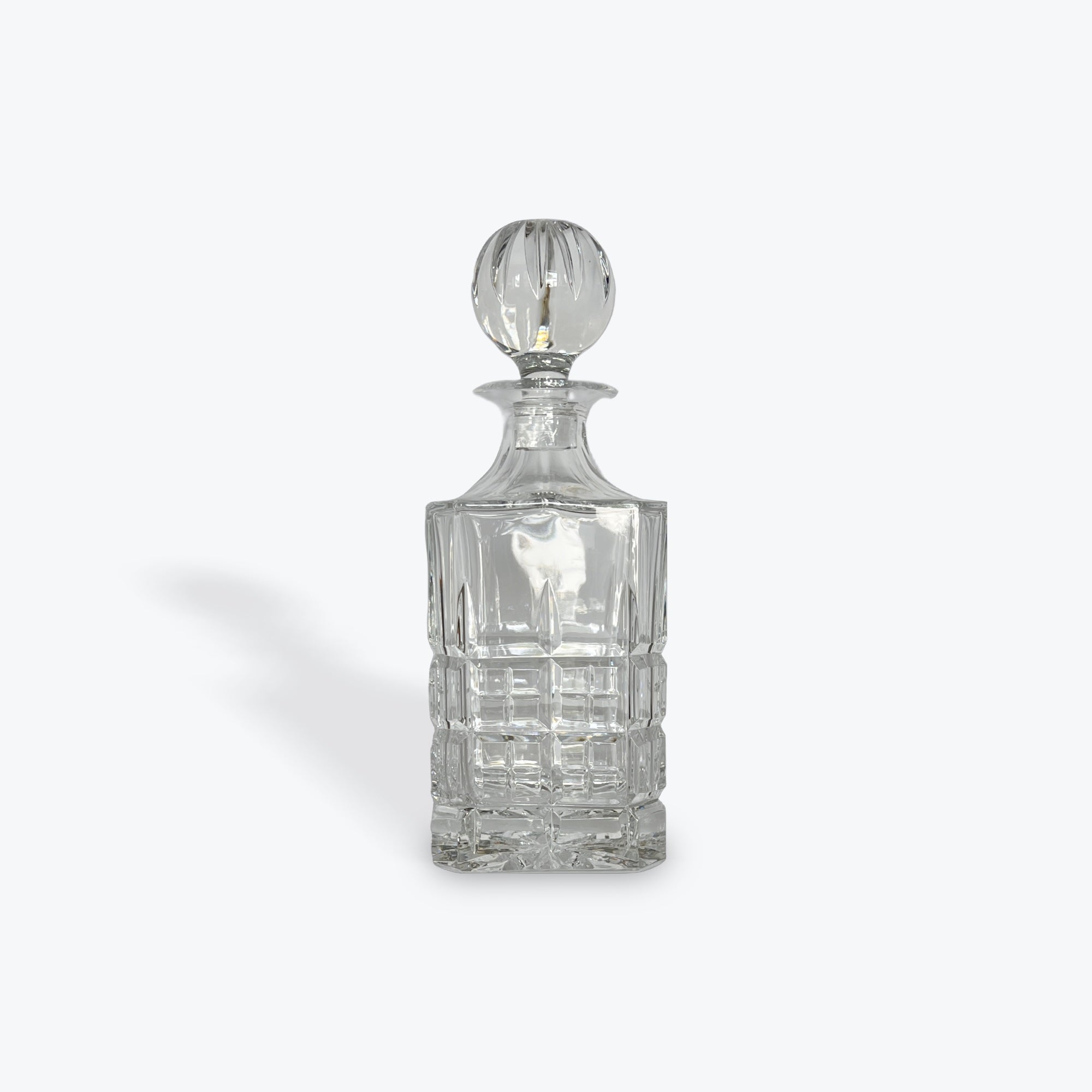 Clear glass decanter with a stopper on a white background