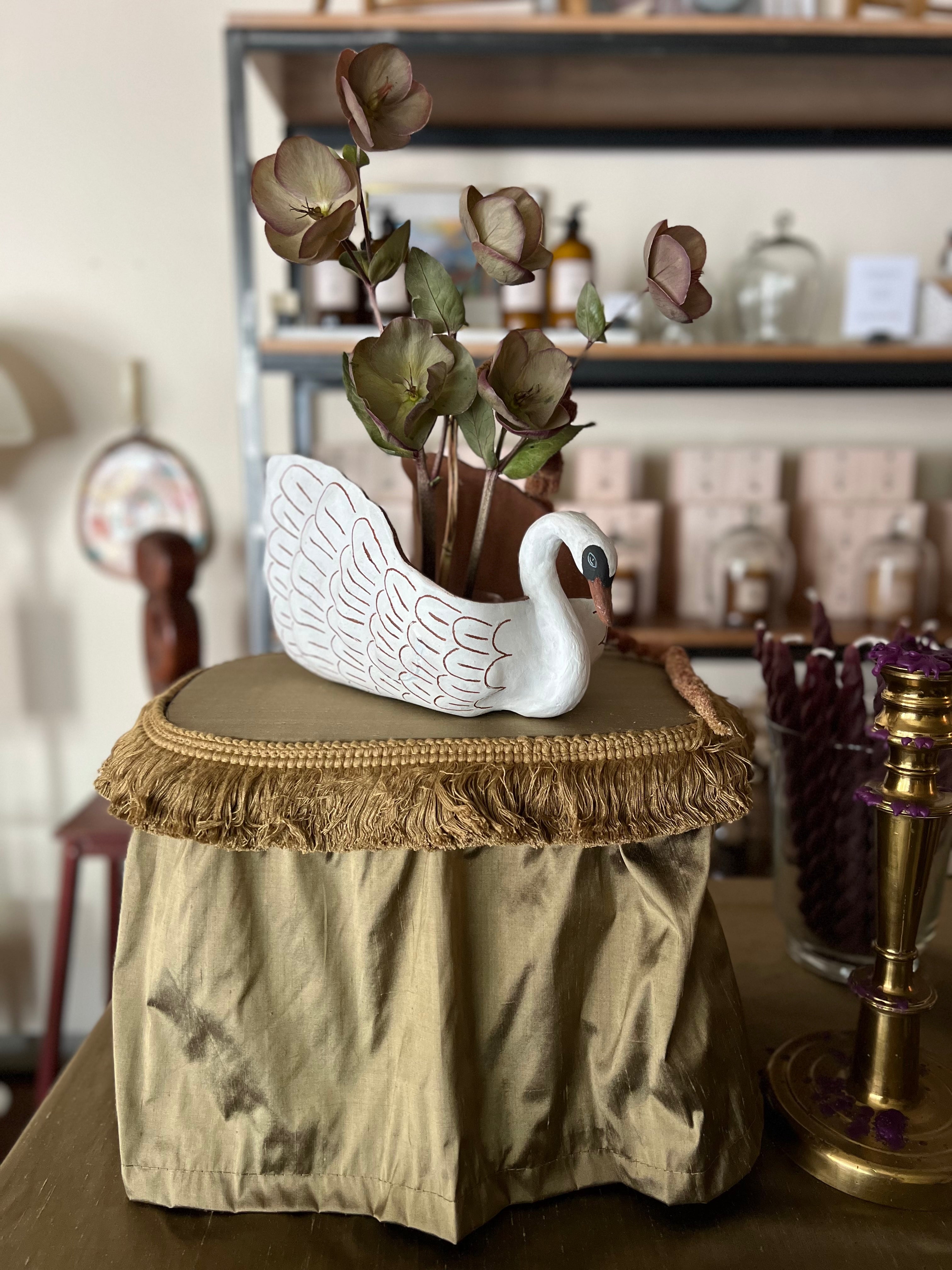 Decorative swan planter on a textured surface with a blurred background