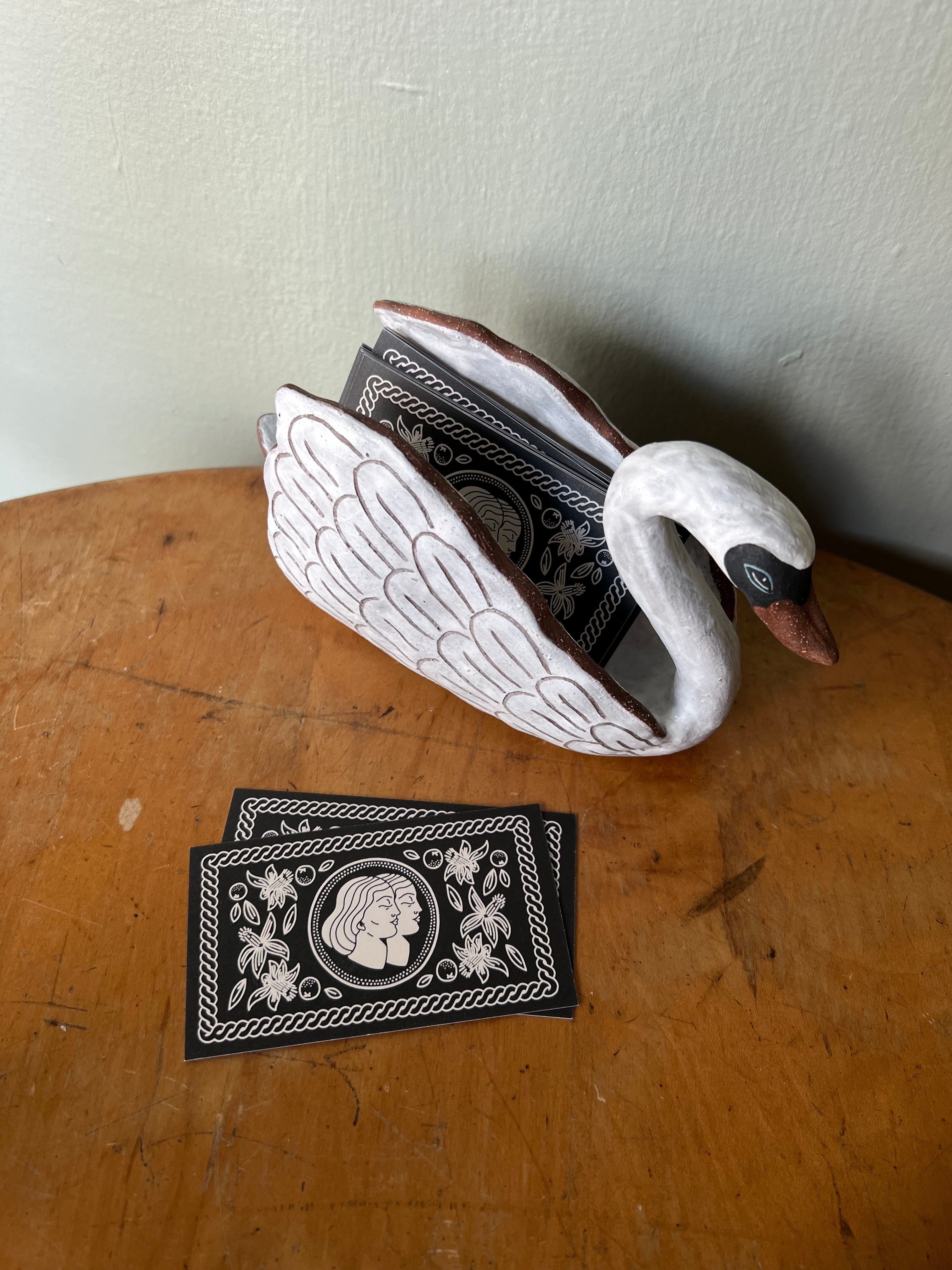 ceramic swan with business cards on a wooden surface