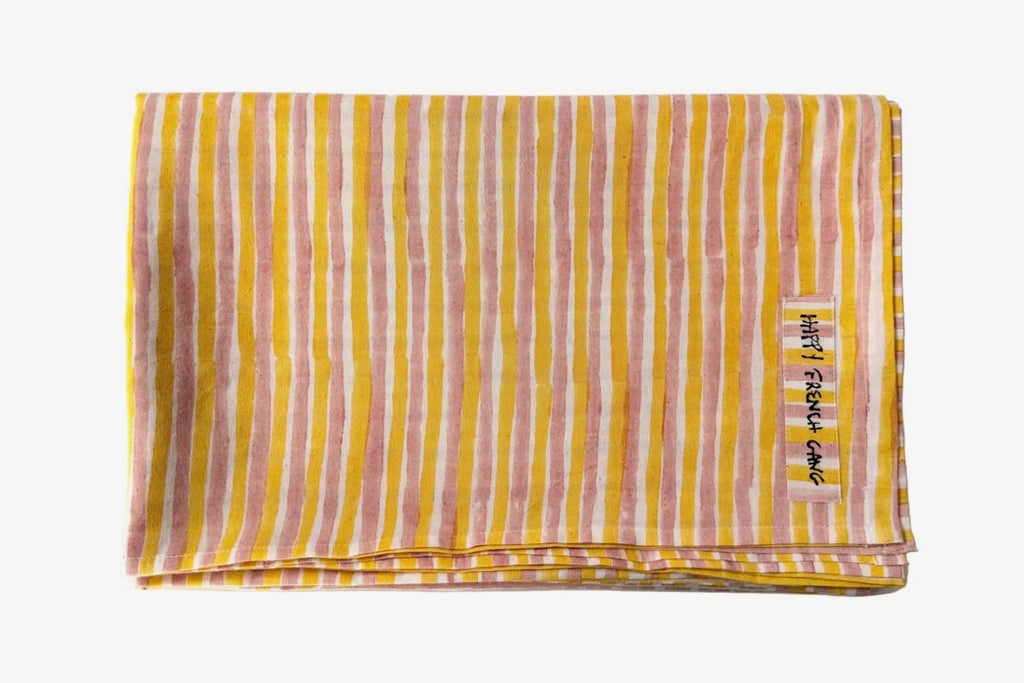 Folded yellow and pink striped blanket with a brand label on a white background